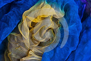 A photo of fabric dyed yellow and blue colors and laid out in an abstract form for use as a background