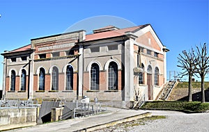 Photo of the facade facing west and the side facing south, of the Bovolenta water pump, illuminated by the sun of a winter afterno