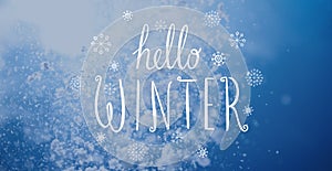 Photo of falling snow in sunny day with Hello Winter lettering.