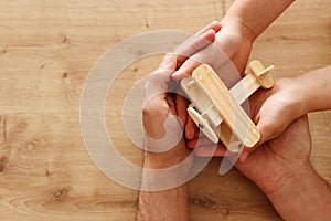 Photo of father and little child holding together wooden toy plane. Happy father`s day and holiday concept. top view, above