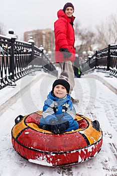 Photo of father of skating son on tubing in winter park