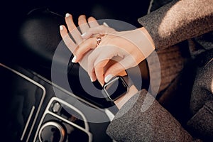 Photo of female hands touching setting of digital smart watch in car