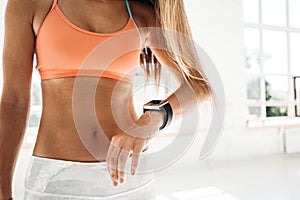 Photo fit woman after workout session checks results on smartwatch in fitness app