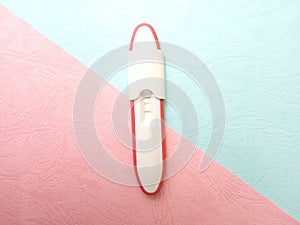 Flat Lay Plastic Pregnancy test pack positive result at texturized Pink and Blue Paper Background photo