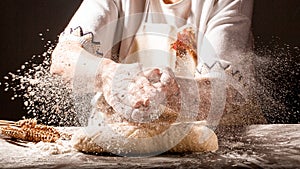 Photo of flour and women hands with flour splash. Cooking bread. Kneading the Dough. Isolated on dark background. Empty space for