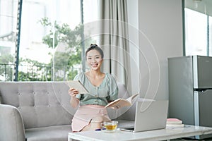 Photo of focused business woman hold pen sit sofa write notes fingers specs in home workstation indoors