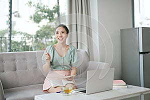 Photo of focused business woman hold pen sit sofa write notes fingers specs in home workstation indoors