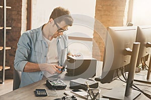 Photo of focused guy software support master sit desk repair hard drive disk operating system wear denim jeans shirt in