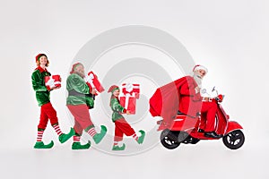 Photo of four people ride moped carry presents bag wear santa elf costume isolated grey color background