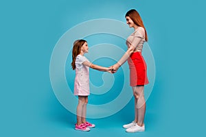 Photo of foxy little lady and mom holding hands standing opposite wear casual clothes isolated blue background