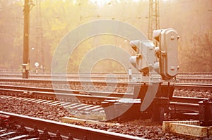Photo of a fragment of a railway track with a small traffic light in rainy weathe