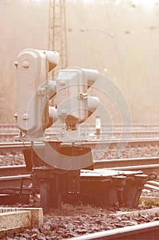 Photo of a fragment of a railway track with a small traffic light in rainy weather