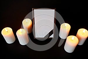Photo frame with black mourning ribbon and candles