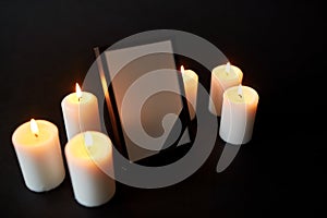 Photo frame with black mourning ribbon and candles