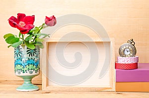 Photo frame with books and flowers on the wooden table