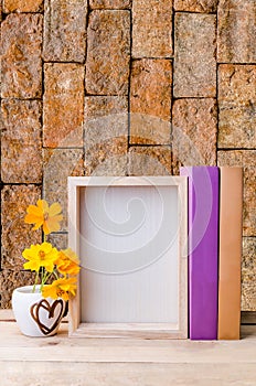 Photo frame, books and flowers on the wooden table with red aged