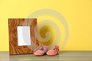 Photo frame and bootees for baby room interior on table