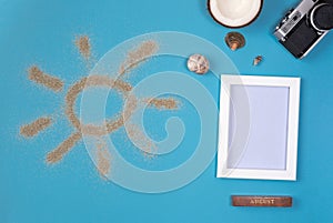 Photo frame and camera on blue background. Sun drawn by the sand on blue background