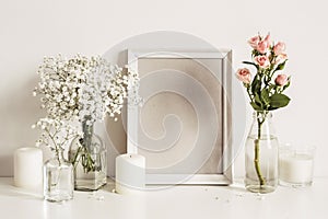 Photo frame, flowers and candles on table wall background. Front view mockup template