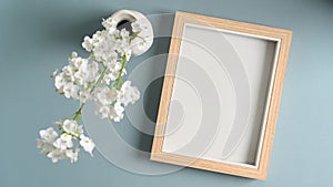 Photo frame and  flowers in vases on blue pastes background.