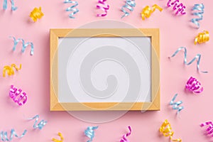 Photo frame, holiday concept. Colorful serpentine and golden stars, on pink background