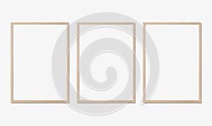 Photo frame mockup. Set of three vertical oak wooden frames on white wall. Template for artwork, painting or poster