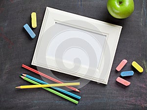 Photo frame and school supplies on blackboard background