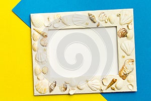 Photo frame with shells on blue and yellow color paper texture b