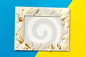 Photo frame with shells on blue and yellow color paper texture b