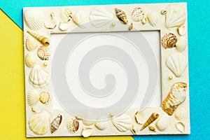 Photo frame with shells on turquoise and yellow color paper texture background. The concept of a summer vacation.  Summer Flatlay