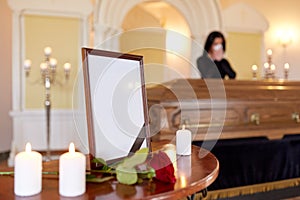 Photo frame and woman crying at coffin at funeral