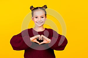 Photo of friendly charming girl toothy smile arms demonstrate heart symbol empty space isolated on yellow color