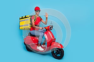 Photo of friendly funky short hair human wear red uniform moped rider fast food delivery waving arm isolated blue color