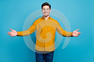 Photo of friendly hospitable guy invite embrace wear yellow shirt jeans isolated blue color background