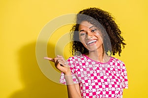 Photo of friendly lovely girl toothy smile direct finger empty space novelty isolated on yellow color background