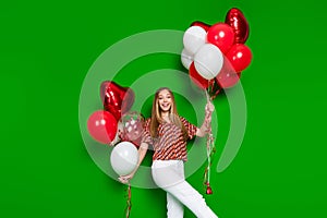 Photo of friendly positive teen dressed print shirt hold palms helium balloons celebrate valentine day isolated on green