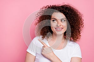 Photo of friendly woman with perming coiffure dressed white t-shirt look directing at promo empty space isolated on pink