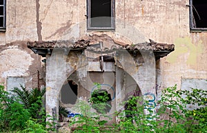 photo of the front entrance of an abandoned building with columns and a broken roof on the porch
