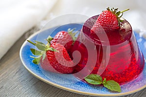 Photo of fruit jelly with fresh strawberry. Healthy food. Strawberry jelly on white plate. Summer dessert with fruit