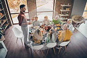 Photo of full big family gathering sit feast meals dinner table father guy tell thanksgiving pray toast multi-generation