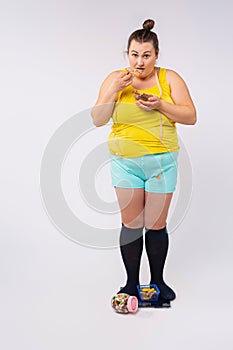 Photo of a full grown obese woman standing on a hanging with a plate of pies. Diabetes. Weakness for sweets. White