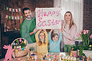 Photo of full idyllic friendly family hold happy eater poster board prepare homemade paint eggs basket indoors