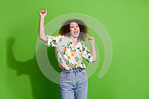 Photo of funky carefree lady wear print shirt screaming yes rising fists isolated green color background
