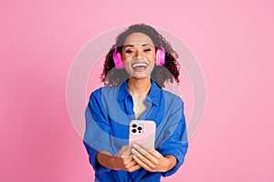 Photo of funky cheerful woman wear trendy clothes listen music bluetooth wireless headphones isolated on pink color