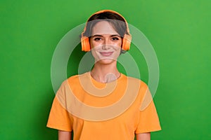 Photo of funky cheerful young lady wear orange outfit headphones enjoying songs isolated green color background