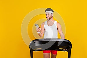 Photo of funky cool guy activewear walking treadmill shopping modern gadget empty space isolated yellow color background