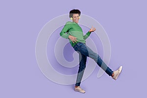 Photo of funky cool guy wear green pullover headphones playing music guitar empty space isolated purple color background