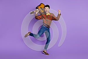 Photo of funky crazy musician guy hold guitar dance wear bow tie plaid shirt jeans shoes isolated purple background