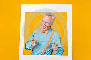 Photo of funky cute retired man wear turquoise shirt suspenders tacking portrait pointing you isolated yellow color