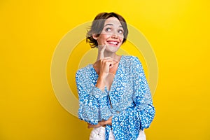 Photo of funky dreamy young woman wear flower print blouse finger chin looking empty space isolated yellow color